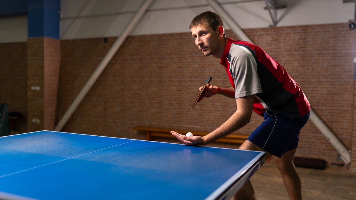 Tischtennisspieler beim Aufschlag mit Ball in der Hand