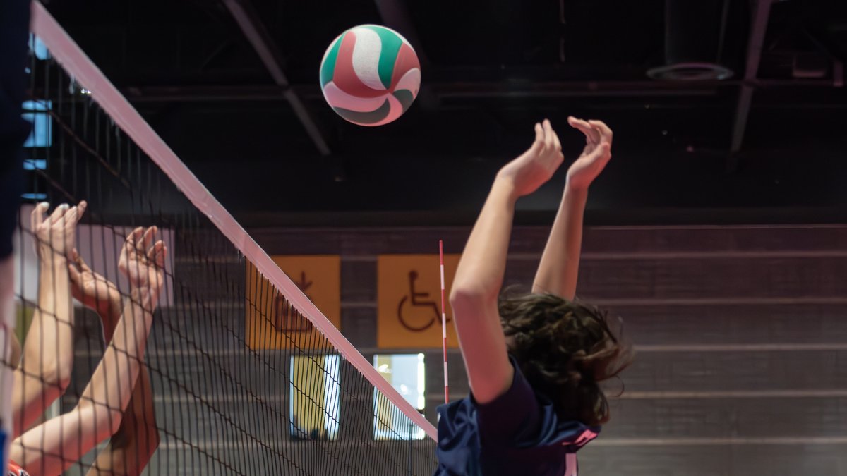Zwei Blockspielerinnen am Netz beim Volleyball, der Ball kommt von oben