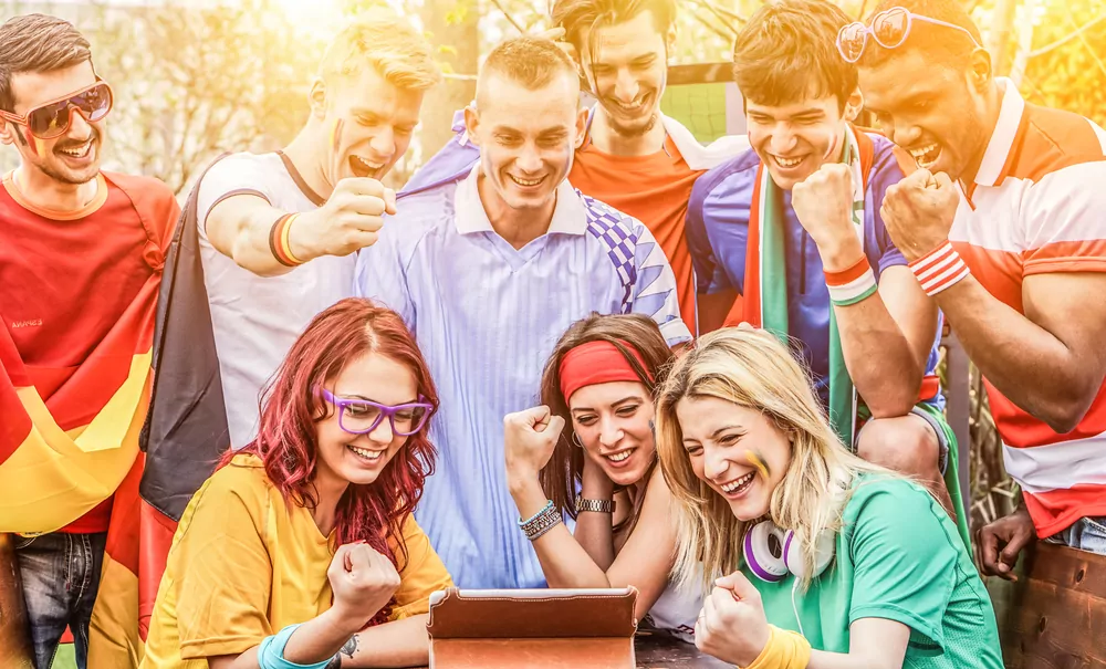 Fußballfans verfolgen gemeinsam ein Spiel auf dem Tablet, ein typischer Einsatz einer Wett App