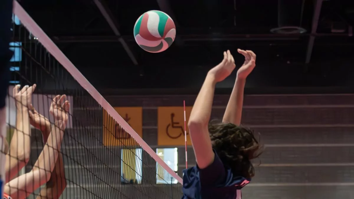 Zwei Blockspielerinnen am Netz beim Volleyball, der Ball kommt von oben